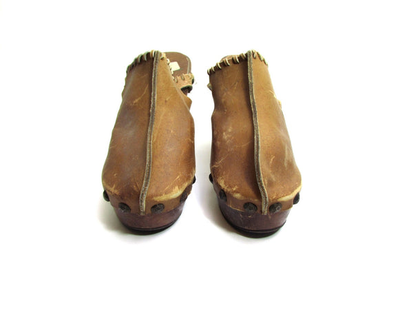 Rare. Vintage 60s 70s clogs with a high heel . They have a whipstitch leather trim along the edge and cutout sides. The leather upper is fastened with brass metal hammered finish tacks. 